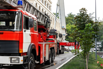 Many fire engine trucks with ladder and safety equipment at accident in highrise tower residential apartment or office building in city center. Emergency rescue at disaster