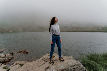 Lake at the peak of the mountain. Foggy lake. Girl is posing on the rocks.