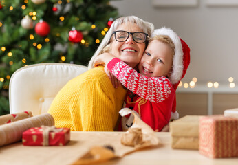 Cheerful child congratulating grandmother at Christmas.