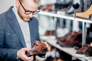 A man in business clothes chooses brown dress shoes in a store.
