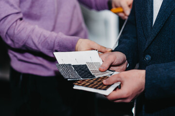 customer-buyer and stylist-fashion designer examine fabric samples for tailoring.