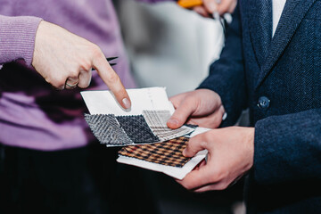 customer-buyer and stylist-fashion designer examine fabric samples for tailoring.