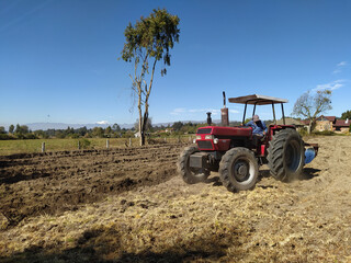 Obraz premium Tractor in a field with a mountain view