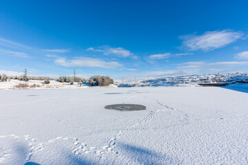 A frozen, icy reservoir covered in fresh snowfall