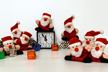 funny santa claus toys with table clock that show five to twelve on blurred painted white background