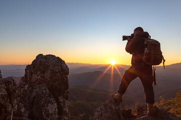 Photographer take photos with mirror camera on peak of mountain at sunset.