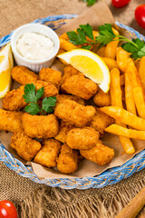 Crispy Fish Bites Snack Size. Deep Fried Pollock Fish Fingers with Tartar Dipping Sauce on a Wooden Board. Selective focus.