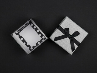 Obraz premium open gift on black. An open silver gift lies in the middle on a black background, top view close-up.