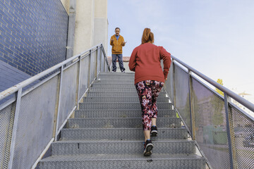 Closeup shot of a woman climbing stairs and a man giving instructions to her