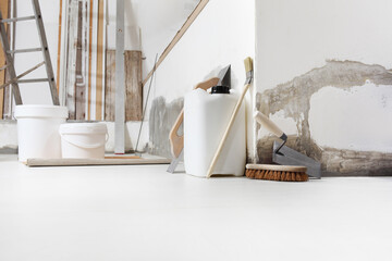 Indoor shot close up frontal view of bricklayer, plasterer or house painter tools on white floor...