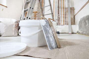 close up of bucket with trowel, spatula and tools, plastering and painting materials on building site background