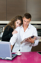 executive couple having a coffe in a kitchen lloking for news