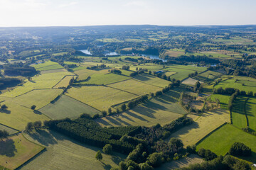 Wide aerial panorama of farmland near Waimes in the Belgian Ardennes, June 2020. Green fields, hedgerows and a network of rural roads and farmhouses form a patchwork pattern across the rolling country