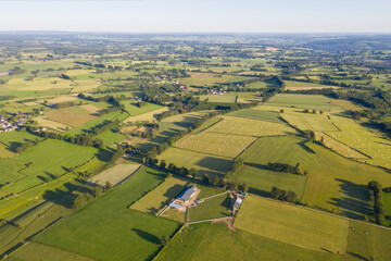 Aerial view over rolling fields and hedgerows near Waimes in the Belgian Ardennes, taken in June 2020. Patchwork farmland, farmhouses and country lanes create a scenic rural landscape under summer sun
