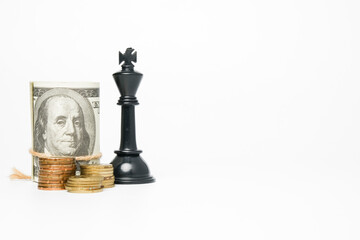 Selective focus of fake cash with black chess king insight on copyspace white background. Cash is...