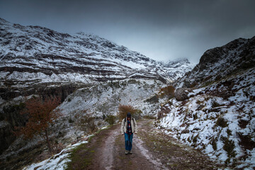 Snowy mountains in the Aragonese Pyrenees. A man walking from Guarrinza pastures to Aguas Tuertas valley, Hecho and Anso, Huesca, Spain.