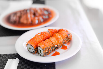 Sushi rolls set. Hand with chopsticks for sushi over white plate. Food at chinese buffet restaurant