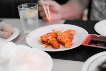 Fish salmon cutlets with sauce on white plate, hand with chopsticks. Food at buffet restaurant