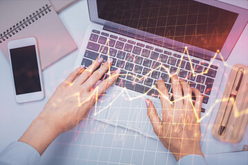 Obraz na płótnie Canvas Double exposure of woman hands working on computer and forex graph hologram drawing. Top View. Financial analysis concept.