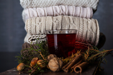 Cup with red tea on a decorated desk and sweaters in the background at home. Autumn and winter healthy food concept