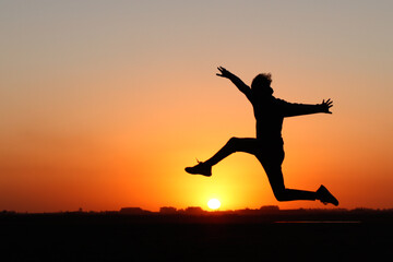 Obraz na płótnie Canvas silueta de chico a contraluz saltando el sol