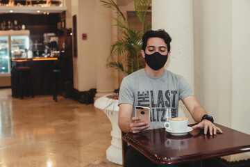 young man in a coffee shop enjoying a couple of drinks using technology