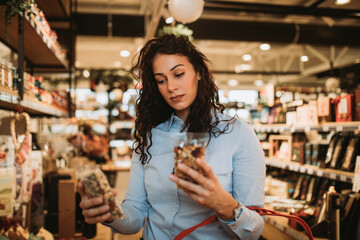 Beautiful young and elegant woman buying some healthy food and drink in modern supermarket or grocery store. Lifestyle and consumerism concept.