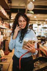 Beautiful young and elegant woman buying some healthy food and drink in modern supermarket or grocery store. Lifestyle and consumerism concept.
