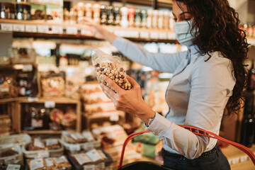 Beautiful young and elegant woman with face protective mask buying healthy food and drink in a...