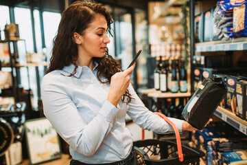 Beautiful young and elegant woman buying some healthy food and drink in modern supermarket or grocery store. Lifestyle and consumerism concept.