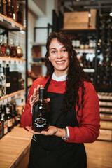 Beautiful and happy female seller working in supermarket or grocery store and selling cured meat products and cheeses.