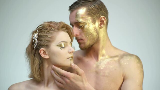 Beautiful couple with golden art makeup touch each other. Fashion gold model. Valentines day.