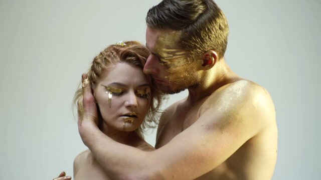Romantic passion dating and love. Beautiful couple with golden art makeup touch each other. Fashion gold model. Valentines day.