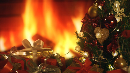 Fototapeta na wymiar New Years Christmas festive background with burning fireplace. Christmas tree. Decorations, red gold balls and glowing bulbs on the tree. Warm home mood. Depth of field, soft focus