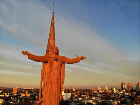 Escultura de Jesus gigante extendiendo los brazos en demostraci&oacute;n de gracia al se&ntilde;or y su campanario completo de fondo en una de las iglesias de la ciudad de Santa Fe - Argentina