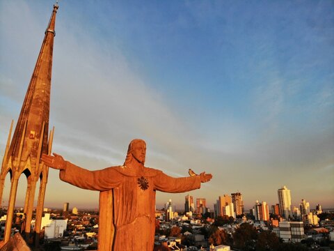 Escultura de Jesus gigante extendiendo los brazos en demostraci&oacute;n de gracia al se&ntilde;or y su campanario completo de fondo en una de las iglesias de la ciudad de Santa Fe - Argentina