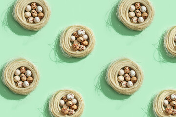 Easter pattern from Quail eggs in straw nest on light green. Flat lay spring Easter