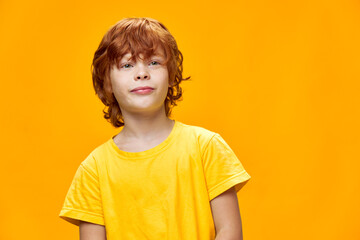 young red-haired child in yellow t-shirt looking forward