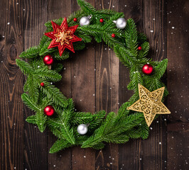 Christmas wreath with decor, Top view of tree fir spruce branches is rolled in a circle and ornament star on black table wood background, New year festive decoration concept