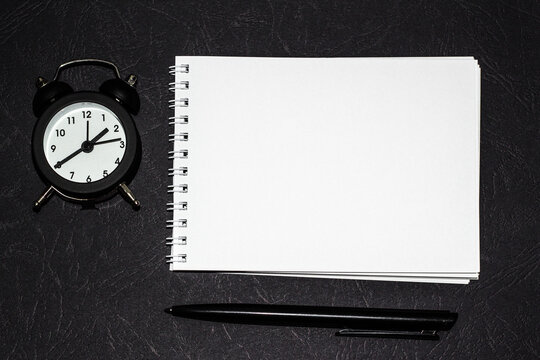 notebooks, watch and a pen on the table for information on a black background . A place for text. Business, marketing, financial concept