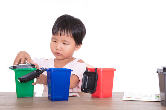 Little children in front of white background are playing sorting garbage bin model
