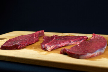 Raw beef steak with spices on a wooden Board. Three pieces of fresh meat. Beef meat without fat. Cooking steak