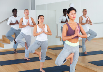 Fototapeta na wymiar Group of young adults attending yoga class at studio