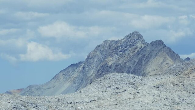 Smooth rotating shot of mystical rocky mountain top in the Sierras with clouds in the sky (60 fps slowed to 24 fps)
