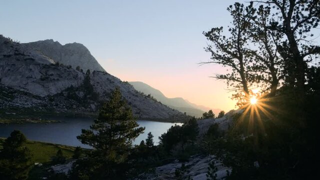 Fantasy landscape in the Sierra Nevadas shows beautiful alpine lake at sunset overlooking layers of mountains (60 fps slowed to 30 fps)
