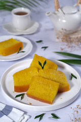 Bika Ambon, Indonesian honeycomb cake with square slices in white plate.
It is made of flour, tapioca, coconut cream, lime leaf, and sugar. Selective focus.
