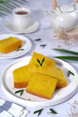 Bika Ambon, Indonesian honeycomb cake with square slices in white plate.
It is made of flour, tapioca, coconut cream, lime leaf, and sugar. Selective focus.
