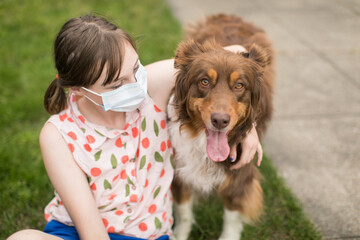 Teen girl wearing mask and hugging pet