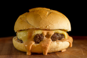 Close up of a homemade classic burger on a chopping wood board, on black background