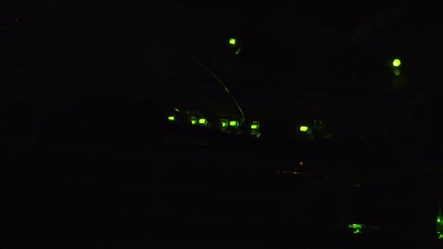 Green LED indicator lights flashing in a dark room, routers processing information